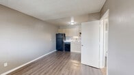 Located at 1881 E Irvington Rd in Tucson, AZ, this efficiently designed one-bedroom, one-bathroom unit offers a smart, functional layout across a single floor. The open-concept main area seamlessly integrates the living room, dining space, and kitchen, creating a versatile and connected environment. The kitchen is well-appointed with light wood cabinetry extending to the ceiling for ample storage, a white quartz countertop, a stainless steel sink, and a full suite of black appliances including a refrigerator, dishwasher, and gas range with overhead ventilation. A dedicated pantry provides additional storage convenience. Durable wood-look flooring runs throughout the main living area, complemented by a textured ceiling. The bedroom is a comfortable retreat featuring plush carpet, a wall-mounted A/C unit, and a window with blinds that invites natural light. It includes access to a dedicated closet, offering practical storage. The bathroom is clean and well-finished, featuring a tiled shower-tub combo, a wood-vanity with quartz countertop, a single basin sink, and a large wall mirror. Neutral gray tones throughout the unit create a cohesive and modern aesthetic.