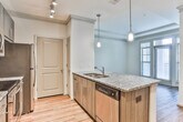 Located at 3905 Chastatee Dr in Duluth, Georgia, this single-floor residence showcases a thoughtfully designed interior with contemporary finishes throughout. The kitchen serves as a central highlight, featuring rich, dark wood cabinetry, granite countertops with a speckled pattern, and a full suite of stainless steel appliances including a range, microwave, refrigerator, and dishwasher. A mosaic tile backsplash adds texture and visual interest, while pendant lighting and a track lighting system illuminate the space effectively. The large kitchen island with a built-in sink provides both functional workspace and a natural gathering point.

Wood-style flooring extends through the main living areas, contributing warmth and continuity, while a raised peninsula subtly defines the transition between the kitchen and living spaces. The bedroom offers plush carpeting underfoot, a ceiling fan, and multiple windows that allow generous natural light to filter in, creating a bright and comfortable retreat.

The bathroom is finished to a high standard, with an L-shaped granite vanity, dual sinks, dark wood cabinetry with sleek hardware, a large mirror, and a glass-enclosed shower. Crown molding details throughout add a refined architectural touch, completing the polished aesthetic of this well-designed home.