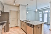Located at 3905 Chastatee Dr in Duluth, Georgia, this single-floor residence showcases a thoughtfully designed interior with contemporary finishes throughout. The kitchen serves as a central highlight, featuring rich, dark wood cabinetry, granite countertops with a speckled pattern, and a full suite of stainless steel appliances including a range, microwave, refrigerator, and dishwasher. A mosaic tile backsplash adds texture and visual interest, while pendant lighting and a track lighting system illuminate the space effectively. The large kitchen island with a built-in sink provides both functional workspace and a natural gathering point.

Wood-style flooring extends through the main living areas, contributing warmth and continuity, while a raised peninsula subtly defines the transition between the kitchen and living spaces. The bedroom offers plush carpeting underfoot, a ceiling fan, and multiple windows that allow generous natural light to filter in, creating a bright and comfortable retreat.

The bathroom is finished to a high standard, with an L-shaped granite vanity, dual sinks, dark wood cabinetry with sleek hardware, a large mirror, and a glass-enclosed shower. Crown molding details throughout add a refined architectural touch, completing the polished aesthetic of this well-designed home.