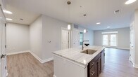 This well-appointed one-bedroom, one-bathroom unit at 1420 W Diehl Rd in Naperville, IL offers a thoughtfully designed open-concept floor plan with modern finishes throughout. The kitchen serves as the centerpiece of the living space, showcasing a large granite-topped island with an undermount sink, sleek pendant lighting, rich dark-toned cabinetry, a subway tile backsplash, and a full suite of stainless steel appliances. Light wood-style flooring flows seamlessly through the kitchen and living areas, enhancing the bright, airy atmosphere created by neutral gray-toned walls and recessed lighting. The spacious living room features elegant French doors that invite natural light and provide outdoor access. The bedroom is carpeted for comfort, includes a ceiling fan with a dedicated window for additional natural light, and connects conveniently to the bathroom. The bathroom is finished with a dark wood vanity, a marble-style countertop, a large framed mirror with contemporary bar lighting, and a walk-in glass shower with clean white subway tile surround. A dedicated closet completes the unit, providing practical storage. The overall design is clean, contemporary, and move-in ready.