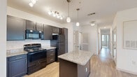 Located at 470 Bulldog Dr in Palm Coast, Florida, this single-story, 3-bedroom, 2-bathroom home offers a well-designed, functional layout. The open-concept living area seamlessly connects the kitchen, dining, and living spaces, creating a bright and airy atmosphere with natural light flowing through multiple windows fitted with blinds. The kitchen is a standout feature, boasting dark espresso cabinetry, granite countertops, a central island with pendant lighting, track lighting, and black appliances including a gas range, built-in microwave, and full-size refrigerator. Wood-style plank flooring runs throughout the main living areas, adding warmth and easy maintenance. The bedrooms are carpeted and generously sized, each equipped with ceiling fans and ample closet space — the primary bedroom includes dual closets. The two bathrooms are finished with tile floors, dark vanity cabinetry, granite countertops, and full tub-shower combinations with white tile surrounds. A dedicated laundry room houses a full-size side-by-side washer and dryer. With five closets throughout, storage is abundant. The overall aesthetic is clean and modern, with a neutral palette that complements the Florida surroundings visible through the bedroom windows.