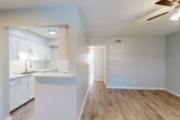 Located at 1900 Avenue S in Huntsville, Texas, this single-story, one-bedroom, one-bathroom unit offers a clean and functional layout designed to maximize its cozy footprint. Light gray walls and wood-look plank flooring run throughout, creating a cohesive and contemporary aesthetic.

The open-concept living, dining, and kitchen area forms the heart of the home. The kitchen is equipped with white shaker-style cabinetry with brushed nickel hardware, a classic white subway tile backsplash, white appliances including a range and refrigerator, and a peninsula with a light-colored countertop that doubles as a breakfast bar and defines the dining space. A stainless steel sink sits beneath overhead cabinetry, maximizing storage.

The living area is bright and open, benefiting from a ceiling fan with a light fixture and natural light from a window with blinds. A hallway connects the main living area to the private bedroom, which is comfortably sized, features its own ceiling fan, a window with natural light, and two closets for ample storage.

The bathroom is finished with white subway tile surrounding a full soaking tub and shower combination, complemented by brushed nickel fixtures, wood-look flooring, and clean white walls, giving it a fresh, modern feel throughout.