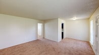 This one-bedroom, one-bathroom unit in Baton Rouge, Louisiana offers a practical and comfortable layout across a single floor. The living room is a generously sized space featuring warm carpet flooring, neutral cream-toned walls, a textured ceiling, and two windows that invite natural light and views of the surrounding greenery. A six-panel entry door adds a classic touch to the welcoming entryway. The bedroom is a well-proportioned room with plush carpet, a textured ceiling with a flush-mount light fixture, a window with blinds for natural light, and a wall-unit air conditioner. It connects directly to a dedicated walk-in closet outfitted with built-in shelving on both sides, providing ample storage. The kitchen is efficiently designed in a galley style with dark wood cabinetry, light countertops, wood-look vinyl plank flooring, and white appliances including a coil-burner range and refrigerator, along with a double stainless steel sink. The bathroom includes a full tub-shower combo with white tile surround, a vanity with storage, and clean, functional finishes throughout. Overall, the unit offers a straightforward and livable layout well-suited for comfortable everyday living.