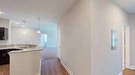 This single-story home offers a comfortable and functional layout across three bedrooms, one bathroom, and a generous combined living and kitchen space. The open-concept kitchen is a standout feature, highlighted by dark espresso cabinetry, granite countertops, a tile backsplash, stainless steel appliances, and a peninsula with pendant lighting that seamlessly connects to the living area. The living room is bright and inviting, with plush carpeting, a ceiling fan, and a glass door flanked by windows that fill the space with natural light. Hardwood-style flooring runs through the kitchen and hallway, creating a clean contrast with the carpeted bedrooms and living areas. The spacious primary bedroom includes a ceiling fan, a large window with natural light, and access to one of three well-organized closets outfitted with wire shelving systems. Additional bedrooms are comfortably sized with soft carpeting and ample closet access. The bathroom features tile flooring, a granite vanity with dark cabinetry, and a full tub and shower combo. A dedicated laundry room houses a full-size washer and dryer with overhead shelving, adding everyday convenience. Neutral tones and clean white trim throughout give the home a fresh, move-in-ready feel.