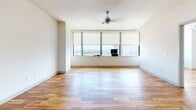 Located on the 19th floor at 1555 Elm St in the heart of Dallas, TX, this one-bedroom, one-bathroom residence offers an impressive high-rise living experience with sweeping views of the downtown skyline. Rich, warm-toned hardwood flooring flows seamlessly throughout the entire unit, creating a cohesive and inviting aesthetic.

The open-concept living and kitchen area is generously proportioned, anchored by a wide bank of floor-to-ceiling windows fitted with roller shades and a ceiling fan, allowing abundant natural light and panoramic city views to define the space. The kitchen is well-equipped with dark espresso cabinetry, granite countertops, a tile backsplash, stainless steel appliances including a refrigerator, electric range, and over-the-range microwave, alongside a stainless steel sink.

The bedroom is a comfortable, well-sized retreat also benefiting from large windows framing striking downtown Dallas views. A dedicated closet provides ample storage. The hallway connects the rooms efficiently, maintaining an organized flow throughout.

The bathroom features large-format tile flooring, dark wall tile in the tub/shower surround, a glass shower enclosure, and dark vanity cabinetry with granite countertops, lending a sleek, modern finish to the space.