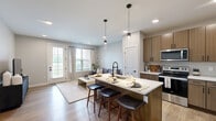 Located at 196 Westfield Rd in Noblesville, Indiana, this thoughtfully designed one-bedroom, one-bathroom residence offers a comfortable and modern living experience across a single floor. The open-concept kitchen and living area serves as the heart of the home, where warm wood-toned cabinetry, a subway tile backsplash, crisp white quartz countertops, and stainless steel appliances create a polished, contemporary kitchen. A central island with pendant lighting and bar seating provides both prep space and a casual dining option. The adjoining living room is bright and welcoming, featuring light hardwood-style flooring, recessed lighting, and large windows alongside a glass-paneled door that fill the space with natural light. The bedroom is a calm, carpeted retreat with a ceiling fan, a generous window with outdoor views, and ample room for a full furniture arrangement. A dedicated closet provides convenient storage. The bathroom is finished with wood-look tile flooring, a glass-enclosed walk-in shower with vertical tile surround, and a sleek vanity with dark hardware accents. Hallways connect the spaces efficiently, and the overall neutral color palette lends a clean, cohesive aesthetic throughout this well-appointed Noblesville residence.