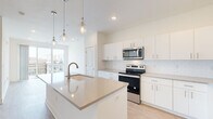 Located at 110 W Hillsdale St in the heart of downtown Lansing, Michigan, this modern single-floor unit offers a thoughtfully designed open-concept layout with contemporary finishes throughout. The kitchen serves as the centerpiece of the living space, showcasing a large quartz-topped island with an undermount sink and stylish pendant lighting overhead. Crisp white cabinetry lines the walls floor to ceiling, complemented by a classic subway tile backsplash and a full suite of stainless steel appliances, including a refrigerator, electric range, over-the-range microwave, and dishwasher. Light wood-tone flooring flows seamlessly through the main living areas, enhancing the bright, airy atmosphere. A stacked in-unit washer and dryer adds everyday convenience. The bedrooms feature plush carpeting and windows with urban views, allowing natural light to fill each room. The primary bathroom offers a generous double-vanity with quartz countertops, white cabinetry, and light wood flooring. A secondary full bathroom includes a tub-shower combination and a single vanity with matching finishes. The unit's clean, neutral palette and modern design elements create a polished, move-in-ready environment well-suited for urban living.