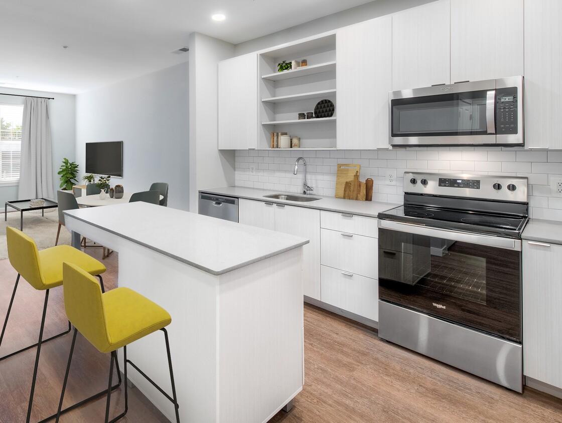 Cocina con encimeras de piedra de cuarzo y gabinetes blancos con placa para salpicaduras de azulejos sobre piso de superficie dura - Kanso Twinbrook