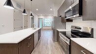 Located at 9001 Metcalf Ave in Overland Park, KS, this thoughtfully designed one-bedroom, one-bathroom residence offers a modern aesthetic across a well-utilized single-floor layout. Light-toned wood-look flooring flows throughout the main living areas, creating a clean and cohesive atmosphere.

The kitchen serves as the centerpiece of the home, showcasing a spacious island with a white quartz countertop, an undermount sink, and dark wood cabinetry. A full suite of stainless steel appliances — including a refrigerator with ice maker, electric range, microwave, and dishwasher — is complemented by a classic subway tile backsplash. Sleek pendant lighting above the island adds a contemporary touch. The kitchen opens toward a windowed living area, allowing natural light to fill the space.

The bedroom features plush carpeting and a window with exterior views, providing a quiet and comfortable retreat. The walk-in closet offers double hanging rods and built-in shelving for ample storage. The bathroom is finished with wood-look tile flooring, a modern vanity with quartz countertop, and a frameless sliding glass shower adorned with marble-style tile. A dedicated in-unit laundry room with a full-size washer and dryer adds everyday convenience to this well-appointed home.