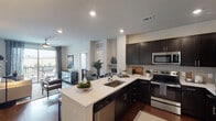 Located in the Lincoln Heights neighborhood of Houston, Texas, this single-floor residence combines contemporary design with functional living. The open-concept kitchen is a standout feature, outfitted with dark espresso cabinetry, stainless steel appliances including a range, microwave, and refrigerator, and a large white quartz peninsula that offers bar seating and seamlessly connects to the dining and living areas. Rich hardwood-style flooring runs throughout the main living spaces, adding warmth and continuity.

The living room is bright and inviting, with a ceiling fan, large sliding glass doors opening to a private balcony, and views of the surrounding community. The dining area sits adjacent to the kitchen, benefiting from the natural light that flows through the open layout.

The primary bedroom features a ceiling fan, generous natural light from large windows, and a serene atmosphere with views of the pool area. Its en-suite bathroom includes dark cabinetry, a white countertop vanity, and access to a walk-in closet. A second bedroom offers a bold accent wall, ceiling fan, and ample natural light. The second full bathroom includes a soaking tub with shower, dark vanity, hardwood-style flooring, and a walk-in closet.