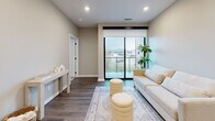 This thoughtfully designed one-bedroom, one-bathroom unit offers a practical and modern layout across a single floor. The open-concept living and kitchen area serves as the heart of the space, featuring warm wood-tone luxury vinyl plank flooring, recessed lighting, and neutral wall tones that create a bright, cohesive atmosphere. The kitchen is well-appointed with taupe shaker-style cabinetry, white subway tile backsplash, light quartz countertops, and a full suite of stainless steel appliances including a refrigerator, range, microwave, and dishwasher. A dining area adjacent to the kitchen comfortably accommodates a small table. The living room benefits from a large sliding glass door that opens to a private balcony, filling the space with natural light and offering outdoor views. The bedroom features plush carpet, a ceiling fan, a wide window with exterior views, and direct access to a dedicated closet with built-in shelving. The bathroom includes a full tub-shower combination, a wood-toned vanity with a white countertop, and matching luxury vinyl plank flooring, maintaining the unit's consistent, contemporary aesthetic throughout.