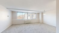 Located on the 9th floor of a residential building at 4500 Connecticut Ave NW in Washington, DC's desirable upper Northwest neighborhood, this two-bedroom, one-bathroom unit offers a practical and comfortable layout across a single floor. The living area is generously proportioned, featuring soft wall-to-wall carpeting, neutral walls, and a wide bank of sliding windows that frame city rooftop views while filling the space with natural light. A pendant light fixture accents the room, and a radiator unit provides in-unit heating. The galley-style kitchen is efficiently designed with warm wood cabinetry, tile flooring, a gas range, and a full-size refrigerator, maximizing storage and functionality within a compact footprint. The spacious primary bedroom is a standout feature of the unit, offering ample room for furnishings along with a built-in closet. The second bedroom is well-sized with carpeting and a window overlooking the surrounding neighborhood. The bathroom is clean and straightforward, featuring a tiled shower-tub combination with chrome fixtures. A dedicated closet provides additional storage. The unit's understated, neutral palette and practical layout offer a solid foundation for personalization in one of DC's most accessible and vibrant corridors.