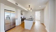 Located in the heart of Philadelphia's sought-after Rittenhouse Square neighborhood, this one-bedroom, one-bathroom residence offers a thoughtfully designed open-concept layout with clean, modern finishes throughout. Light hardwood flooring runs continuously across the entire unit, creating a cohesive and airy feel.

The kitchen and living area form the central hub of the space, where a sleek kitchen island with a dark countertop and matte black faucet serves as the focal point. White cabinetry lines the walls, complemented by stainless steel appliances including a French door refrigerator, electric range with a stainless hood, and built-in microwave. Pendant lighting above the island adds a refined touch to the open layout.

The living area flows naturally from the kitchen, bathed in natural light from multiple windows that frame elevated views of the Philadelphia skyline — a standout feature of this upper-floor unit.

The bedroom is a well-proportioned retreat with large windows offering continued city views, a dedicated closet, and built-in storage cabinetry. Recessed lighting and white walls maintain the clean, minimalist aesthetic throughout.

The bathroom features light tile flooring, a floating vanity with a round mirror, and a clean, functional design. The entrance provides a welcoming transition into the main living space, completing this well-appointed urban residence.