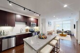 Located at Century Square in College Station, TX, this well-appointed 2-bedroom, 3-bathroom residence offers a thoughtfully designed single-floor layout. The open-concept kitchen and living area serves as the heart of the home, anchored by a granite-topped island with bar seating. Rich dark cabinetry, a white subway tile backsplash, stainless steel appliances — including a refrigerator, range, microwave, and dishwasher — and track lighting complete the kitchen. Gleaming hardwood floors extend throughout the main living area, which features large windows that invite abundant natural light and views of the surrounding greenery. The living room offers a comfortable, airy atmosphere with recessed lighting and clean white walls. The primary bedroom features plush carpet, a ceiling fan, and direct access to a spacious en-suite bathroom outfitted with a dual-sink granite vanity, tile flooring, and an adjacent walk-in closet. The second bedroom is equally well-appointed with soft carpet and a ceiling fan. Two additional bathrooms serve the home, each finished with granite countertops and dark cabinetry. An in-unit washer and dryer provide added convenience, rounding out this polished and functional residence.