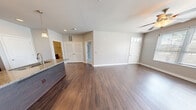 This thoughtfully designed one-bedroom, one-bathroom unit at 3712 Lake Huron Drive in Valparaiso, Indiana offers a comfortable and modern living experience. The open-concept layout seamlessly connects the kitchen and living room, creating a spacious, airy feel enhanced by rich hardwood-style flooring that flows throughout the main living areas. The kitchen is a standout feature, boasting rich dark cabinetry, granite countertops, a peninsula island with an integrated sink and pendant lighting overhead, and a full suite of stainless steel appliances including a gas range, microwave, and refrigerator. Recessed lighting adds a polished finish to the space. The living area is bright and welcoming, with large windows fitted with blinds that allow natural light to fill the room, along with a ceiling fan for added comfort. A private entry door with a transom window and stone exterior accents lends a charming curb appeal. The bedroom features plush carpeting, a generous window with an outdoor view, and access to a dedicated closet. The bathroom is elegantly finished with large-format tile surround in the tub-shower combo and hardwood-style flooring. The unit offers a clean, neutral palette throughout, making it move-in ready.