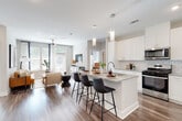This single-story residence is designed around an open-concept floor plan that seamlessly connects the kitchen, dining, and living areas into one cohesive, light-filled space. Rich wood-look flooring flows throughout the main living areas, grounding the bright, neutral palette of soft grays and crisp whites.

The kitchen is a central highlight, showcasing white shaker cabinetry extending to the ceiling, granite countertops, and a classic subway tile backsplash. A generous island with seating for multiple guests serves as both a prep space and a social hub, illuminated by sleek pendant lighting. Stainless steel appliances, including a gas range, over-the-range microwave, and full-size refrigerator, complete the well-appointed cooking space.

The living room benefits from an abundance of natural light streaming through large windows and a glass door, creating an airy, welcoming atmosphere enhanced by a ceiling fan overhead.

The bedrooms offer a calm retreat, each carpeted for comfort and sized to accommodate generous furnishings. The primary bedroom connects to a bathroom featuring granite-topped vanity cabinetry and a walk-in closet, while wood-look flooring carries through the bathroom and hallway spaces. The overall ambiance throughout is clean, contemporary, and move-in ready.