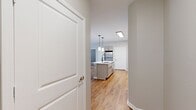 This well-appointed 1,020 sq ft apartment at 2365 Sir Barton Way, Unit 1227, in Lexington, KY offers two bedrooms, two bathrooms, and a thoughtfully designed single-floor layout. The open-concept kitchen and living area serves as the heart of the home, showcasing light wood-tone cabinetry with modern hardware, white quartz countertops, a tile backsplash, stainless steel appliances including a refrigerator, electric range, and microwave, and a central island with a matte black faucet and undermount sink illuminated by pendant lighting. Warm hardwood flooring flows throughout the main living areas, complemented by neutral gray walls and an abundance of natural light from windows with white plantation-style blinds. The living room features a ceiling fan and a private exterior door with a transom window. The primary bedroom measures 180 sq ft with plush carpet, a ceiling fan, and direct access to a well-finished en suite bathroom featuring a dual-sink vanity with quartz counters, matte black fixtures, and a soaking tub. The second bedroom also features carpet and a window. Two closets provide ample storage. A dedicated laundry room houses a full-size washer and dryer. The unit offers a clean, modern aesthetic throughout.