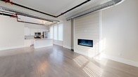 This thoughtfully designed single-floor unit blends modern finishes with industrial character in a striking and functional layout. The open-concept living and dining area is defined by rich hardwood flooring, large windows that invite abundant natural light, and a standout shiplap accent wall framing a built-in electric fireplace. Exposed silver HVAC ductwork and black piping trace the ceiling throughout, lending the space a contemporary loft-inspired aesthetic.

The kitchen is well-appointed with white cabinetry, granite countertops, a classic subway tile backsplash, and a full suite of stainless steel appliances including a gas range, microwave, and refrigerator. A kitchen island with additional counter space adds both functionality and flow to the layout.

The bedroom features plush wall-to-wall carpeting, exposed overhead piping consistent with the industrial design theme, and direct access to a generously sized walk-in closet with built-in shelving. The bathroom is finished with large-format tile flooring, a granite-topped gray vanity with ample storage, a wide mirror with overhead lighting, and dual heated towel racks for added comfort. A walk-in shower completes the bathroom's clean, modern look. Overall, the space offers a cohesive blend of warmth, practicality, and urban style.