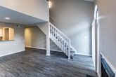 This two-story residence in the Sycamore neighborhood of Memphis, Tennessee, offers a thoughtfully designed layout with 1 bedroom and 1.5 bathrooms across two levels. The main floor features an open living area with vaulted ceilings that lend a sense of spaciousness, complemented by large windows that allow natural light to fill the room. A ceiling fan and recessed lighting provide both comfort and illumination. The living area flows toward a pass-through kitchen, where granite-look countertops, white shaker-style cabinetry, and black appliances—including a full-size refrigerator and dishwasher—come together for a clean, functional workspace. Light wood-look flooring runs throughout the main level, creating a cohesive and easy-to-maintain surface. A hallway with recessed lighting connects the main living spaces and leads to the staircase, which ascends to the upper level. The second floor houses the primary bedroom with carpeted flooring and access to the full bathroom, as well as a half bath on the lower level for added convenience. Neutral wall tones and clean white trim are consistent throughout, contributing to a bright, move-in-ready ambiance.