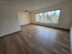 Located at 505 Wood Place, Unit #1405, in Everett, Washington, this 3-bedroom, 2-bathroom apartment spans 870 square feet across a single floor in the Olympic Park community. Light-toned hardwood flooring flows consistently throughout the unit, creating a cohesive and clean aesthetic.

The open-concept living room is bright and spacious, featuring large corner windows with verdant tree views, a ceiling fan, and baseboard heating. It connects directly to the galley-style kitchen, which is equipped with light maple cabinetry, dark laminate countertops, a coil electric range, a dishwasher, a refrigerator, and ample upper and lower cabinet storage.

The primary bedroom measures 170 square feet and includes a large window with outdoor views and a closet. The additional two bedrooms each feature hardwood floors and closets, with one room showcasing a painted cinder block accent wall. Both bathrooms are finished with light maple vanities, dark countertops, mirrored medicine cabinets, and hardwood flooring.

Throughout the unit, neutral white walls, textured ceilings, and consistent wood-toned finishes contribute to a clean, functional, and well-lit living environment ideal for comfortable everyday living.