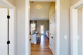 Located at 180 Hughes Rd in Madison, Alabama, this well-appointed single-story home offers two bedrooms and two bathrooms across a thoughtfully designed floor plan. Warm wood-look flooring runs throughout the main living areas, tying together a cohesive and modern aesthetic defined by neutral tones and clean lines.

The open-concept kitchen and living room serve as the heart of the home. The kitchen features white cabinetry, a subway tile backsplash, dark countertops, stainless steel appliances, and a central island with bar seating illuminated by sleek pendant lighting. The adjacent living room is bright and airy, with elevated ceilings, a ceiling fan, and large windows that invite natural light and outdoor views.

The primary bedroom is a comfortable retreat, highlighted by a generous window with outdoor views, light wood flooring, and soft neutral walls. Both bathrooms are finished with white cabinetry, dark countertops, and modern black hardware accents — one featuring a tub-shower combination with clean white tile surround.

A dedicated laundry room with a window and shelving adds everyday convenience. Two hallways and two closets provide practical storage throughout. The home's consistent use of warm neutrals, modern fixtures, and natural light creates an inviting, move-in-ready atmosphere.