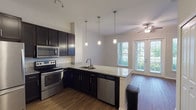 This single-floor residence offers a thoughtfully designed open-concept layout that seamlessly connects the kitchen and living area. The kitchen is a standout feature, showcasing dark espresso cabinetry, granite countertops, and a full suite of stainless steel appliances, including a range, microwave, refrigerator, and dishwasher. A peninsula with an undermount sink and pendant lighting above creates a natural gathering point and adds a modern, stylish touch. Rich hardwood-style flooring extends throughout the main living area, complemented by generous natural light streaming in through sliding glass doors that open to the outdoors.

The bedrooms are carpeted for comfort and feature ceiling fans and large windows with blinds that invite ample natural light and outdoor views. One bedroom includes direct access to an en-suite bathroom equipped with a glass-enclosed shower, dark vanity cabinetry, and tile flooring. A second full bathroom features a full soaking tub and shower combination, a dark vanity, and wood-style flooring. The overall color palette throughout the residence is neutral and clean, creating a bright, airy ambiance. The functional floor plan and quality finishes make this a well-balanced and comfortable living space.