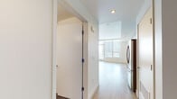 Located at 1133 S Hope St in the heart of downtown Los Angeles, this modern single-floor unit offers a clean, contemporary design throughout. The open-concept living and kitchen area is anchored by expansive floor-to-ceiling windows that flood the space with natural light and frame sweeping city skyline views. A sliding glass door leads to a private balcony, further connecting the interior to the vibrant urban landscape outside. Light wood-tone flooring runs throughout, lending warmth and continuity to the space. The kitchen is thoughtfully appointed with sleek flat-front cabinetry in a soft gray finish, a light-colored subway tile backsplash, white quartz countertops, and a full suite of stainless steel appliances including a gas range, built-in microwave, dishwasher, and a French door refrigerator with an ice and water dispenser. Ample upper and lower cabinetry provides generous storage. The bedroom is well-proportioned with recessed lighting and a double-door closet offering substantial storage. The bathroom is finished with large-format tile flooring, a white vanity with an integrated sink, and a full soaking tub with an overhead shower. Recessed lighting and a clean white palette throughout the unit contribute to a bright, modern ambiance well-suited to urban living.
