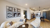 Located on Chamberlain Lane in Louisville, Kentucky, this single-floor residence offers a thoughtfully designed open-concept layout with contemporary finishes throughout. The living area is bright and welcoming, featuring light wood-style flooring, neutral tones, and large windows that frame outdoor views and flood the space with natural light. A sliding glass door provides access to a private balcony, extending the living space outdoors.

The kitchen is a standout feature, equipped with stainless steel appliances including a refrigerator, range, microwave, and dishwasher. White upper cabinetry pairs with wood-toned lower cabinets, complemented by granite countertops and a tile backsplash. A central island with pendant lighting and bar seating serves as both a functional workspace and a casual dining spot.

The bedrooms are well-appointed with plush carpet, generous windows with blinds and draping curtains, and ample natural light. Each room offers a calm, restful atmosphere. A walk-in closet with built-in shelving provides generous storage. The bathroom features granite countertops, white cabinetry, a large vanity mirror, and a soaking tub. Throughout the residence, a cohesive neutral palette and modern design elements create a polished, comfortable living environment.