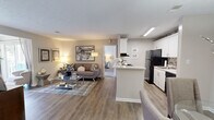 Located at 1110 Garden Walk Blvd in Atlanta, GA, this well-appointed 2-bedroom, 2-bathroom residence offers a thoughtfully designed single-level floor plan. The open-concept living area welcomes you with warm wood-style flooring that flows seamlessly from the entryway through the dining and living spaces. The living room is bright and inviting, featuring large windows with draping curtains that allow natural light to fill the room. Adjacent to the living area, the dedicated dining space is anchored by a pendant light fixture overhead, creating an intimate setting. The kitchen features white cabinetry, a tile mosaic backsplash, black appliances including a refrigerator and range, and a stainless steel sink, all complemented by a convenient breakfast bar peninsula. The primary bedroom is generously sized with plush carpeting and direct access to its own bathroom. The second bedroom also features carpet flooring and ample natural light. Both bathrooms include a clean, tiled tub-shower combination. A dedicated in-unit laundry area houses a full-size washer and dryer with additional shelving for storage. Textured ceilings and neutral tones throughout give the home a cohesive, modern aesthetic, making it a comfortable and functional living space.