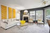 This single-story, 2-bedroom, 2-bathroom residence offers a thoughtfully designed layout that maximizes functionality throughout. The open-concept living room is a standout space, featuring a tiled wood-burning fireplace set against a bold navy accent wall, soft carpeted flooring, a textured ceiling, and multiple windows that invite natural light and outdoor views. The adjoining kitchen is separated by a curved peninsula with granite-style countertops and bar seating, making it ideal for casual dining. Warm wood cabinetry, a range hood, and hardwood-style flooring complete the kitchen's practical design.

The primary bedroom offers a comfortable footprint with plush carpet, neutral walls, and a dedicated closet. The second bedroom features a teal accent wall, a walk-in closet, and a window with ample natural light. Both bedrooms are served by their own full bathrooms, each outfitted with wood-tone vanity cabinetry, granite-style countertops, and a tub-shower combination. The primary bath includes a separate vanity area with additional storage. A hallway connects all rooms, contributing to the unit's organized and efficient flow.