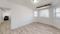 Located at 7609 S Coles Ave in Chicago's South Side, this two-bedroom, one-bathroom unit offers a practical and well-appointed single-floor layout. Throughout the space, light wood-look flooring and crisp white walls create a clean, cohesive aesthetic, while textured ceilings add a classic touch.

The primary bedroom is a generously sized room featuring multiple windows that bring in natural light and views of the surrounding neighborhood. Exposed overhead ductwork adds an industrial character to the space. The second bedroom is more intimate in scale, also benefiting from natural light through a single window and the same light flooring.

The kitchen is efficiently laid out and well-equipped, featuring gray lower cabinetry topped with granite-style countertops, a black gas range, and a stainless steel refrigerator. A window above the counter area allows for natural light during meal preparation.

The bathroom is finished with large-format light gray tile surrounding a full soaking tub with an overhead shower, giving it a clean and contemporary feel.

A central hallway connects the rooms, with multiple doorways providing easy flow throughout the unit. The overall design is understated and move-in ready, offering a functional and comfortable living environment on Chicago's South Side.
