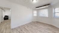 Located at 7609 S Coles Ave in Chicago's South Side, this two-bedroom, one-bathroom unit offers a practical and well-appointed single-floor layout. Throughout the space, light wood-look flooring and crisp white walls create a clean, cohesive aesthetic, while textured ceilings add a classic touch.

The primary bedroom is a generously sized room featuring multiple windows that bring in natural light and views of the surrounding neighborhood. Exposed overhead ductwork adds an industrial character to the space. The second bedroom is more intimate in scale, also benefiting from natural light through a single window and the same light flooring.

The kitchen is efficiently laid out and well-equipped, featuring gray lower cabinetry topped with granite-style countertops, a black gas range, and a stainless steel refrigerator. A window above the counter area allows for natural light during meal preparation.

The bathroom is finished with large-format light gray tile surrounding a full soaking tub with an overhead shower, giving it a clean and contemporary feel.

A central hallway connects the rooms, with multiple doorways providing easy flow throughout the unit. The overall design is understated and move-in ready, offering a functional and comfortable living environment on Chicago's South Side.