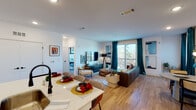 Located at 2395 Herodian Way SE in Atlanta, GA, this modern single-floor residence offers a thoughtfully designed open-concept layout finished with warm hardwood-style flooring throughout the main living areas. The kitchen is a standout feature, showcasing sleek white cabinetry extending to the ceiling, a subway tile backsplash, quartz countertops, stainless steel appliances, and a spacious central island with bar seating — ideal for both everyday dining and entertaining. The kitchen flows seamlessly into the living and dining areas, which are bathed in natural light from large sliding glass doors that open to a private balcony with open outdoor views. The primary bedroom is a serene retreat featuring plush carpet, large windows, a ceiling fan, and a bold accent wall. Its en-suite bathroom offers a wide double-vanity with quartz counters, modern lighting, and a glass-enclosed shower. A second bedroom provides comfortable living space with easy access to a full bathroom complete with a tub-shower combination and quartz vanity. Clean white walls, recessed lighting, and contemporary finishes throughout create a cohesive, modern ambiance well-suited for stylish urban living in the greater Atlanta area.