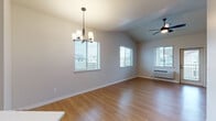 Located at 5069 Countryside St NE in Salem, Oregon, this single-story home presents a clean, contemporary design with a neutral color palette and light wood-style flooring carried throughout. The open living and dining area is a standout feature, boasting vaulted ceilings that lend a sense of spaciousness and height. Multiple windows along the exterior walls allow generous natural light to fill the space, while a modern chandelier and ceiling fan with light kit provide layered overhead lighting. A wall-unit HVAC system is also present in this area.

The kitchen is positioned adjacent to the main living space and is outfitted with light wood cabinetry, white countertops, and black appliances including a refrigerator, range, and over-range microwave. A peninsula with seating overhang provides additional prep and dining space, creating a functional and connected layout.

The bedrooms feature the same light wood flooring and neutral walls, with windows offering views of the surrounding neighborhood. Closet access is available within the bedroom areas. The bathrooms include a full bath with a soaking tub, patterned tile flooring, a wood-tone vanity with white countertop, and a separate stall shower with a clean white surround in an additional bath.