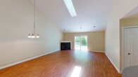 This two-floor home is designed with functional living spaces distributed across both levels. The main living area makes a strong impression with its vaulted ceiling, skylight, and warm hardwood flooring. A corner fireplace serves as a focal point, while sliding glass doors open to the outdoors, filling the room with natural light and views of surrounding greenery. A chandelier adds a finishing touch to the space.

The kitchen is well-equipped with stainless steel appliances, including an electric range, over-the-range microwave, refrigerator, and dishwasher. Abundant oak cabinetry provides generous storage, and granite-style countertops complete the functional layout. Hardwood flooring continues throughout the kitchen.

The upper level features a carpeted open landing area, leading to bedrooms with neutral tones, plush carpet, and standard closets with built-in rods. One bathroom includes a single vanity, hardwood flooring, and a tub-shower combination, while a second full bathroom offers a tub-shower unit, vanity, and large mirror.

The attached garage accommodates a vehicle comfortably and is equipped with an automatic door opener. Consistent warm beige tones and hardwood flooring throughout the home create a cohesive, neutral aesthetic.