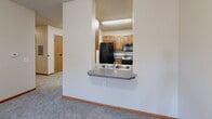 Located at 1015 Southeast 8th Street in Minneapolis, MN, this two-bedroom, one-bathroom unit offers a practical and well-organized single-floor layout. The open-concept living, dining, and kitchen area creates a cohesive central space. The kitchen features warm wood-tone cabinetry, gray laminate countertops, a double stainless steel sink, and black appliances including a refrigerator, range, and over-the-range microwave, all set on durable hardwood-style flooring. A pass-through counter connects the kitchen to the carpeted living and dining area, which benefits from large windows that invite natural light and outdoor views of the surrounding neighborhood. Both bedrooms are carpeted and offer a comfortable sense of space. The primary bedroom is notably spacious and includes a double-door closet, while the second bedroom also features a closet for added storage. The unit includes a total of four closets, providing ample storage throughout. The full bathroom is finished with tile flooring, a shower-tub combination, and accessibility-friendly grab bars. Textured ceilings and warm wood-tone doors are consistent design elements throughout, contributing to a cohesive and functional living environment.