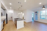 Located at 17011 W Little York Rd in Houston, TX, this one-bedroom, one-bathroom residence offers a thoughtfully designed open-concept layout finished with light wood flooring throughout. The combined living, dining, and kitchen area forms the heart of the home, anchored by a central island featuring a dark granite countertop, an undermount sink, and elegant pendant lighting above. The kitchen is well-appointed with gray shaker-style cabinetry, a white subway tile backsplash, dark countertops, and a full suite of stainless steel appliances including a refrigerator, range, and microwave. Large windows and a glass-panel door in the living area invite abundant natural light and views of the surrounding greenery. The spacious bedroom is equipped with a ceiling fan, two bright windows with outdoor views, and direct access to both a walk-in closet with multi-level shelving and the bathroom. The bathroom offers a dual-sink vanity with dark granite countertops, gray cabinetry, wall-mounted mirrors, and matching storage cabinets. A dedicated laundry room with a full-size washer and dryer and built-in shelving adds convenience, while a pantry provides additional storage. The overall aesthetic is clean, bright, and modern.