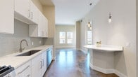 Located in the heart of downtown Houston, this one-bedroom, one-bathroom unit offers a well-designed urban living experience. The open layout connects the kitchen and living area seamlessly, creating an efficient yet comfortable flow throughout the space. Polished concrete floors run throughout, lending an industrial-modern aesthetic that is both durable and visually striking.

The kitchen is outfitted with white shaker-style cabinetry, a mosaic tile backsplash, quartz countertops, stainless steel appliances including a gas range, built-in microwave, dishwasher, and refrigerator, and a peninsula with pendant lighting overhead — ideal for casual dining or meal prep.

The living area is bright and airy, with tall ceilings and large double-hung windows that frame panoramic views of the Houston downtown skyline, flooding the space with natural light. The bedroom offers similar cityscape views through its own set of windows, providing a comfortable and well-lit retreat.

The bathroom features a double-sink vanity with crisp white cabinetry, quartz countertops, brushed metal hardware, and large mirrors, delivering a clean, contemporary finish. The entry area provides convenient access adjacent to the kitchen. Overall, the unit presents a cohesive modern design with quality finishes throughout.