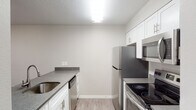 This single-floor residence offers a well-organized layout that balances comfort and functionality throughout its living spaces. The kitchen serves as a practical centerpiece, featuring white shaker-style cabinetry, granite-style countertops, and a full suite of stainless steel appliances including a refrigerator, electric range, built-in microwave, and dishwasher. Light wood-look flooring runs underfoot, and overhead fluorescent lighting ensures a bright, efficient workspace. A pass-through counter connects the kitchen to an adjacent dining or flex area, which opens directly to an outdoor patio through a sliding glass door, inviting natural light and easy outdoor access.

The living room is a comfortable gathering space highlighted by a tile-surround fireplace, large windows with outdoor views, and a ceiling fan with a light fixture overhead. Wood-look flooring continues throughout, adding warmth and cohesion. The bedrooms are carpeted for added comfort, each featuring ceiling fans and windows that bring in natural light. The bathrooms are finished with white cabinetry, granite-style countertops, undermount sinks with brushed nickel fixtures, and a tub-shower combination, maintaining the clean, contemporary aesthetic found throughout the home.
