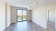 Located at 500 North Andrews Avenue in the heart of Fort Lauderdale, FL, this thoughtfully designed one-bedroom, one-bathroom residence offers a clean, modern aesthetic throughout. Wood-look plank flooring runs continuously through the main living areas and bedroom, lending warmth and cohesion to the space.

The open kitchen is outfitted with flat-panel white cabinetry extending to the ceiling, a marble-inspired tile backsplash, quartz countertops, and a full suite of stainless steel GE appliances including a range, microwave, dishwasher, and refrigerator. Track lighting above illuminates the workspace effectively.

The living area is bright and open, flowing naturally toward a full-height sliding glass door that opens onto a private balcony with a railing, offering elevated views of the surrounding Fort Lauderdale cityscape and lush tree canopy. A large picture window in the bedroom further captures these views, filling the room with natural light. The bedroom includes built-in wardrobe cabinetry and a walk-in closet with integrated shelving and hanging space.

The bathroom features a floating wood-tone vanity with a white quartz countertop and undermount sink, a backlit LED mirror, marble-look tile flooring, and a glass-enclosed walk-in shower with matching marble-look tile surround. The overall ambiance is contemporary, light-filled, and well-appointed throughout.