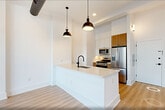 This contemporary 720 square foot apartment offers a thoughtful blend of style and practicality. The open-concept design seamlessly integrates the kitchen, living, and dining areas, creating a spacious feel within the compact floor plan. The kitchen boasts sleek wood cabinetry, stainless steel appliances, and a modern pendant light, perfect for culinary enthusiasts.

The bedroom, measuring 130 square feet, features large windows that flood the space with natural light and offer urban views. Light-toned wood flooring throughout the apartment adds warmth and continuity to the design. The bathroom showcases a clean, modern aesthetic with a wooden vanity and a combination tub-shower.

Industrial-inspired elements, such as exposed pipes and ductwork, add character to the space while maintaining a polished look. The apartment's neutral color palette, primarily whites and light woods, creates a bright and airy atmosphere. This efficient layout maximizes every square foot, making it an ideal choice for those seeking a stylish yet functional urban living space.