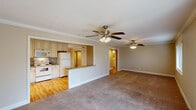 This well-appointed single-story home in Metairie, Louisiana offers three bedrooms and two bathrooms across a generously sized floor plan. The open-concept living and kitchen area serves as the heart of the home, where warm hardwood flooring transitions seamlessly from the kitchen into the main living space. The kitchen is equipped with cream-toned cabinetry featuring detailed glazing, granite countertops, recessed lighting, and white appliances including a range, microwave, and refrigerator. A peninsula counter connects the kitchen to the living area, creating an ideal space for casual dining or entertaining. Crown molding and ceiling fans are found throughout, adding a classic, polished touch. The spacious living room features plush carpeting and a sliding glass door that invites natural light and provides outdoor access. Each bedroom is carpeted, with ample closet space, and windows dressed with blinds. The primary bedroom connects to a bathroom vanity area with granite counters and a walk-in closet, while the bathroom includes a full tub and shower combination. A light-filled hallway connects the bedrooms, with hardwood flooring reinforcing the home's cohesive design. The neutral color palette throughout creates a clean, versatile ambiance.