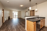 Located in West Des Moines, Iowa, this 2-bedroom, 2-bathroom residence offers a thoughtfully designed single-floor layout that balances comfort and functionality. The open-concept living and kitchen area serves as the heart of the home, featuring warm hardwood-style flooring that flows throughout. The living room is anchored by a cozy fireplace and a large sliding glass door that opens to a balcony, flooding the space with natural light and providing views of the surrounding cityscape.

The kitchen is well-equipped with stainless steel appliances, including a full-size refrigerator, range, and built-in microwave, complemented by warm wood cabinetry, dark countertops, and a peninsula with pendant lighting — ideal for casual dining or entertaining.

Both bedrooms are carpeted for comfort and feature windows with blinds that invite natural light. The generously sized primary bedroom includes a walk-in closet and a private en-suite bathroom with a walk-in shower, wood vanity, and tile flooring. A second full bathroom with similar finishes serves the additional bedroom. The home also includes a dedicated laundry area and two closets, rounding out a practical and complete living space.