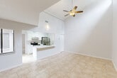 Located at 239 Oak Tree Circle in Daytona Beach, Florida, this single-story, 2-bedroom, 2-bathroom home offers a well-organized layout with a clean, neutral aesthetic throughout. The exterior presents a stucco facade framed by mature palm trees, Spanish moss-draped oaks, and manicured hedging, creating an inviting Florida tropical setting with a generous concrete driveway.

Inside, light-toned ceramic tile flooring flows consistently through all living areas. The living room is bright and open, featuring sliding glass doors that provide direct outdoor access and views of the surrounding greenery, along with additional windows that bring in ample natural light. A separate area of the living space features notably elevated ceilings with high clerestory windows, adding a sense of volume and airiness.

The galley-style kitchen is efficiently designed with white shaker cabinetry, white quartz countertops, stainless steel appliances including a range and refrigerator, and a utility closet, keeping the space organized and functional.

The primary bedroom is generously sized with a large window overlooking the tropical landscaping. The second bedroom is comparably comfortable with natural light.

Both bathrooms are finished with clean, modern details. One features a tub-shower combination with full tile surround and a decorative mosaic accent border. The other offers a white vanity with quartz countertop, brushed nickel fixtures, and tile flooring.