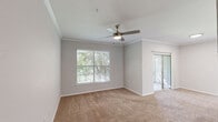 Located at 12055 Sabo Rd in Houston, TX, this single-floor, one-bedroom, one-bathroom unit offers a practical and well-appointed layout. The open-concept living and kitchen area is defined by light wood-look flooring, with plush carpet transitioning into the living space. The kitchen is equipped with stainless steel appliances, including a refrigerator, range, and microwave, complemented by white cabinetry, a subway tile backsplash, and a marble-look countertop peninsula with a double sink — ideal for both cooking and casual dining. The bedroom features soft carpeting, a ceiling fan, and two windows fitted with blinds that allow for ample natural light and views of the surrounding greenery. A dedicated walk-in closet with wire shelving and hanging rods provides generous storage. The bathroom includes a single-sink vanity with white cabinetry and a large mirror, a tub-shower combination with tiled surround, and updated light fixtures. A separate laundry area accommodates a full-size washer and dryer side by side, adding everyday convenience. The unit's clean, neutral palette and thoughtful layout make it a functional and comfortable living space.