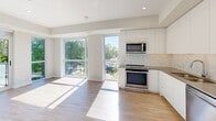 Located at 2475 Hurontario Street in Mississauga, this contemporary 2-bedroom, 2-bathroom unit offers a thoughtfully designed open-concept layout with clean, modern finishes throughout. The kitchen is a standout feature, equipped with stainless steel appliances including a gas range, built-in microwave, dishwasher, and refrigerator, complemented by sleek white cabinetry, a marble-style herringbone backsplash, and light hardwood-style flooring that extends throughout the unit. Large floor-to-ceiling windows flood the space with natural light and frame lush, tree-lined outdoor views. The living area opens directly to a private balcony with glass railing, offering pleasant greenery and open-sky vistas. The primary bedroom features mirrored sliding closet doors and expansive windows with balcony access, while the second bedroom also benefits from generous window placement and ample natural light. Both bathrooms are finished with modern fixtures; the main bathroom showcases marble-style tile surrounding a full soaker tub and shower, while the second bathroom features a sleek wood-toned vanity with a white countertop and large mirror. A welcoming hallway connects all areas of the unit, completing this bright and well-appointed home.