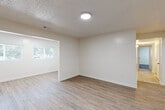 This single-floor unit offers a bright and functional layout designed with clean, modern finishes throughout. The open living and dining areas are finished with durable wood-look flooring and neutral white walls, creating a light and airy atmosphere. Natural light filters in through windows, adding warmth to the open flow between spaces. A welcoming entry door leads directly into the main living area, which connects seamlessly to a windowed dining space.

The kitchen is well-equipped and thoughtfully designed, featuring crisp white shaker cabinetry, granite countertops, a classic subway tile backsplash, and white appliances including a range and full-size refrigerator. Light tile flooring completes the clean, cohesive look of this functional cooking space.

The bedrooms are carpeted with plush grey carpet, providing a comfortable and quiet retreat. Each room benefits from natural light through windows and offers generous wall space. A closet with a paneled door is present in one of the rooms, adding practical storage.

The bathroom is finished in a clean, neutral palette with tile flooring, a tub-shower combination, a toilet, a pedestal sink, and a wall-mounted medicine cabinet mirror. Textured ceilings are found throughout much of the unit, adding a subtle architectural detail to the overall design.