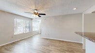 This single-floor unit offers a practical and comfortable layout with consistent wood-look flooring throughout, lending a clean and cohesive aesthetic across all rooms. The open living area is a welcoming space, featuring a ceiling fan with integrated lighting, a textured ceiling, and multiple windows dressed with horizontal blinds that allow natural light to filter in while maintaining privacy. Neutral gray walls provide a versatile backdrop throughout the unit.

The kitchen is designed in a galley style, with warm-toned wood cabinetry, dark granite-look countertops, and a full suite of appliances including a stainless steel refrigerator, electric range, and dishwasher. A breakfast bar counter connects the kitchen to the main living area, creating an open and functional flow between the two spaces.

The bedrooms are generously proportioned, each equipped with ceiling fans and ample natural light. One bedroom features a wall-mounted heating unit and a closet with louvered doors, adding to the room's practicality.

A dedicated in-unit laundry closet houses a full-sized washer and dryer, concealed behind louvered bifold doors. The bathroom is finished with clean white tile surrounding a full-sized soaking tub and shower combination. Throughout the unit, white baseboards and recessed lighting add polished finishing details.