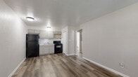 Located at 416 Sundown Dr in Independence, Missouri, this one-bedroom, one-bathroom unit offers a practical and efficiently organized single-floor layout. Wood-look luxury vinyl plank flooring runs consistently throughout the space, providing a cohesive and easy-to-maintain foundation in every room.

The combined kitchen and living area forms the heart of the unit. The kitchen is equipped with gray shaker-style cabinetry, a white subway tile backsplash, a double-basin stainless steel sink, and black appliances including a refrigerator and electric range. Open wood shelving adds a functional accent. The adjoining living area provides enough room for essential furnishings and includes a front entry door with a window that brings in natural light, along with a wall-mounted air conditioning unit.

A hallway connects the main living area to the bedroom and bathroom. The bedroom is a comfortable, well-proportioned room featuring a window with blinds that allows natural light, wood-look flooring, and a textured ceiling. The bathroom is clean and straightforward, outfitted with a stand-alone shower stall, toilet, vanity, and matching wood-look flooring. The overall aesthetic is neutral and move-in ready throughout.