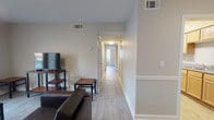 Located at 3525 Gentian Blvd in Columbus, Georgia, this single-floor unit offers a practical and well-organized layout designed for comfortable everyday living. Light wood-style flooring runs consistently throughout the space, complementing the neutral gray-toned walls that create a clean, cohesive aesthetic.

The living area provides a welcoming gathering space with room for seating and entertainment, flowing naturally into a central hallway that connects the rest of the unit. The galley-style kitchen features light wood cabinetry, speckled countertops, and white appliances including a range, dishwasher, and refrigerator, maximizing efficiency within its linear footprint.

The unit includes multiple bedrooms, each with light flooring, ceiling fans or fixtures, and windows fitted with blinds that allow natural light while maintaining privacy. The bathrooms are functional and straightforward — one includes a full tub and shower surround with built-in corner shelving, while the second features a single-sink vanity with wood cabinetry, a granite-style countertop, and a wall-mounted mirror with overhead lighting.

A dedicated in-unit laundry area houses a full-size top-loading washer and dryer with overhead wire shelving, adding significant convenience. Overall, the space presents a tidy, move-in ready environment with consistent finishes throughout.